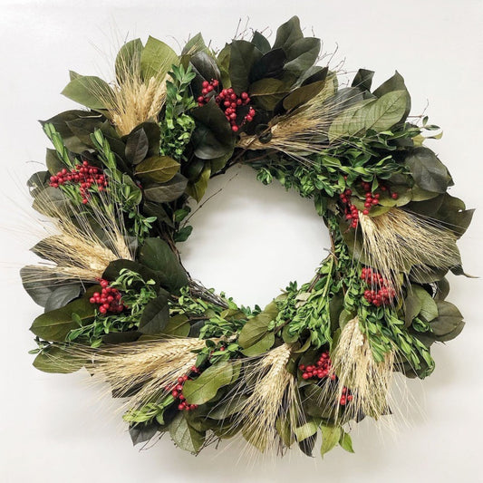 Green Christmas wreath with leaves, berries, and wheat on a white background