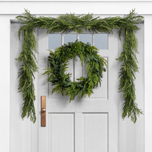 green cedar christmas wreath and garland on a white door
