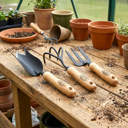 H Potter × DeWit 3-piece bulb planting tool set with tulip trowel, 3-tine cultivator, and hand fork on garden bench
